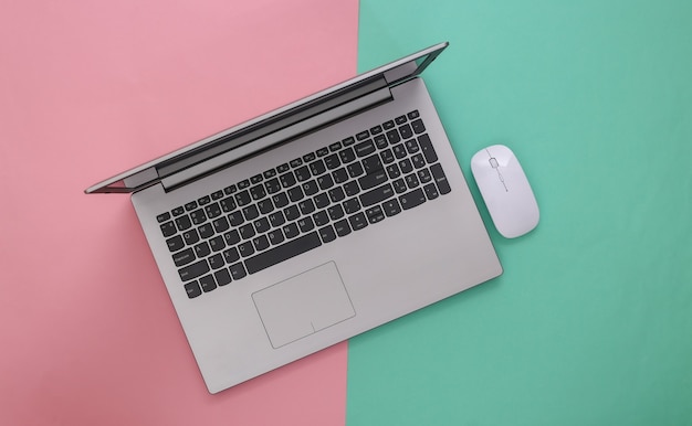 Laptop with pc mouse on pink blue background. Online workspace. Remote work. Studio shot. Top view. Flat lay