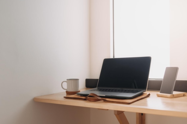 Laptop workspace on wooden desk by the windows