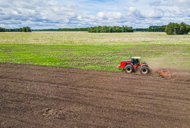 A large agricultural machine cultivates the land. The view from the top. Plowing land for planting crops. photos from the bird's eye view with a quadcopter