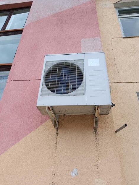 A large air conditioner on a pink wall with the word air on it.