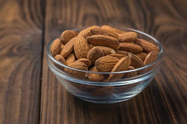 Large almonds in a glass Cup on a wooden table