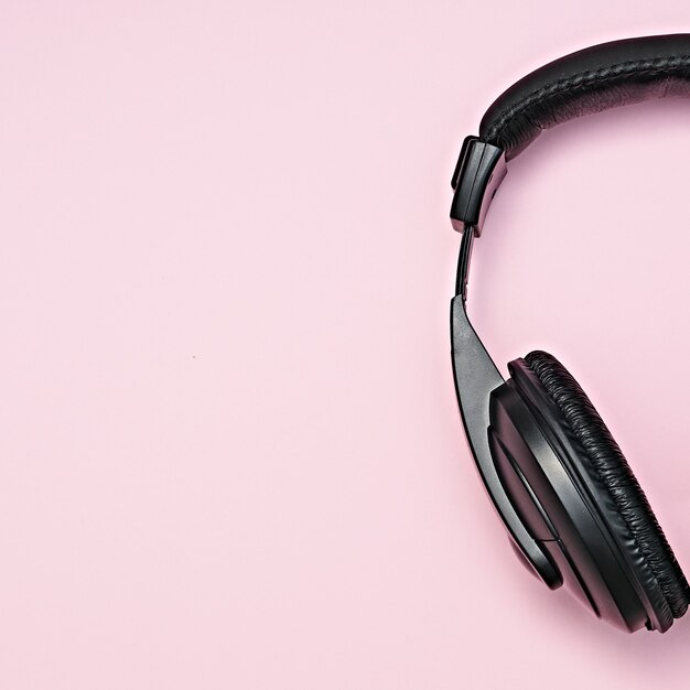 Large, black headphones lie on a colored background