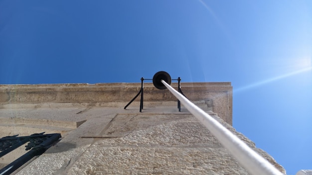 Large black metal bell on the wall of the house with a thick white rope