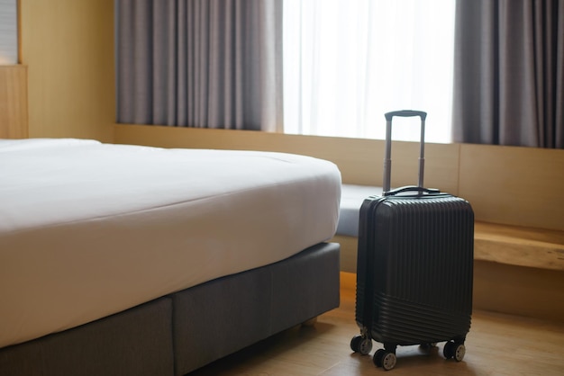 A large black suitcase sits at the foot of the bed in a luxury hotel