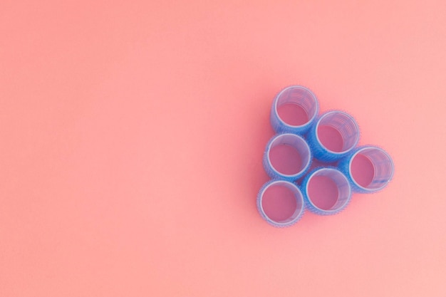 Large blue hair curlers on a bright pink background