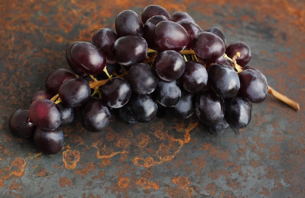 a large bunch of black grapes on a metal background with rust