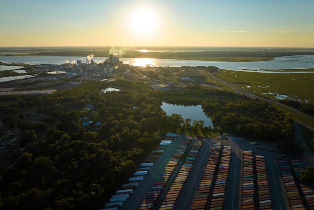 Large cargo container yard with many freight containers and big factory manufactory structure Production and distribution of produced goods