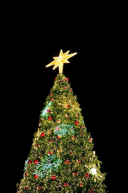 Large Christmas fir tree with big star, red ball ornament and glittering lighting in the night. Christmas and New Year holiday