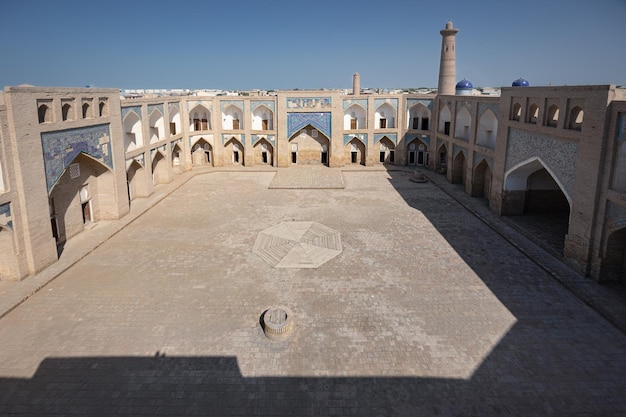 Large courtyard of ancient madrasah decorated with traditional blue tiles at day Khiva Uzbekistan