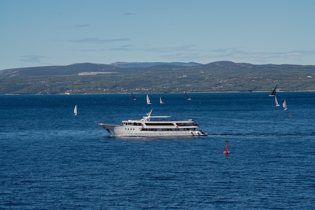 A large cruise ship leaves the port There are a lot of sailing ships and yachts in the sea