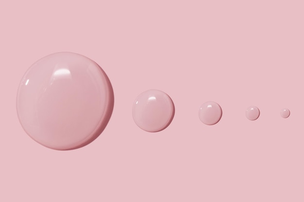 Large drops of cosmetic serum liquid water gel on a pink background