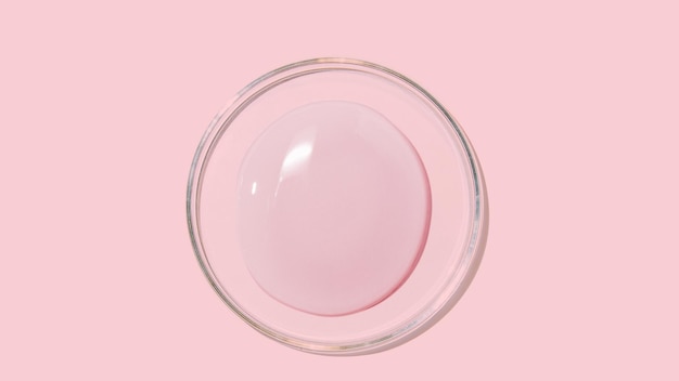 Large drops of cosmetic serum liquid water gel on a pink background