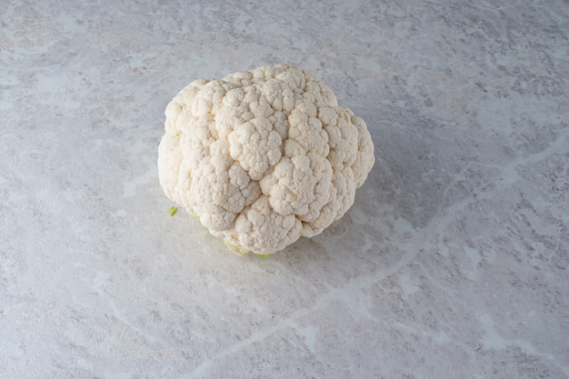 A large, fresh head of cauliflower on a light marble .  the diet.