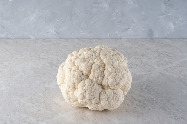 A large, fresh head of cauliflower on a light marble .  the diet.