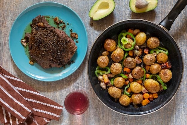 Large fried piece of ham meat in pan with vegetables spices lunch fried piece of meat and potatoes