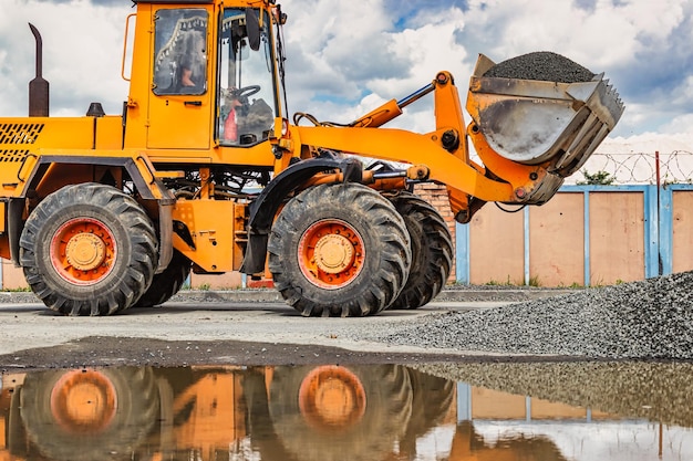 A large front loader transports crushed stone or gravel in a bucket at a construction site or concrete plant Transportation of bulk materials Construction equipment Bulk cargo transportation