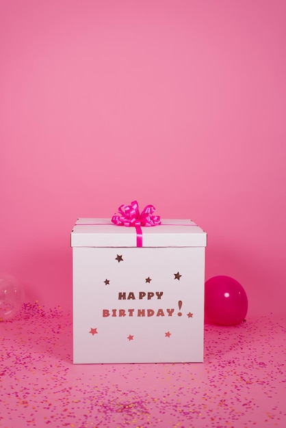 Large gift box birthday gift with pink bow with balloons next to the background