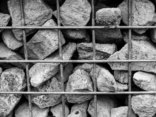 Large gray stones behind bars Metal lattice behind which a background of granite fragments