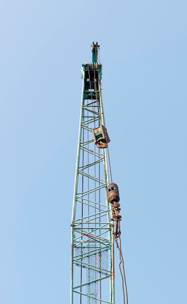 Large green crane boom with hooks with blue sky background