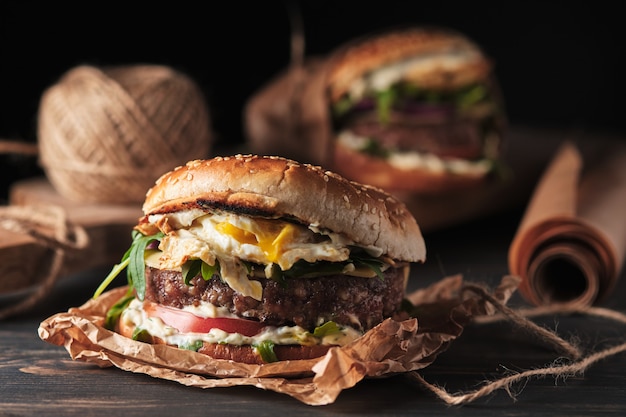 Large grilled burger with vegetables on a wooden board