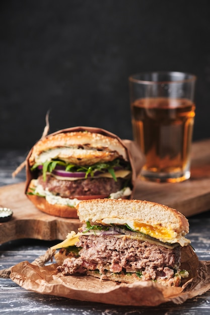 Large grilled burger with vegetables on a wooden board