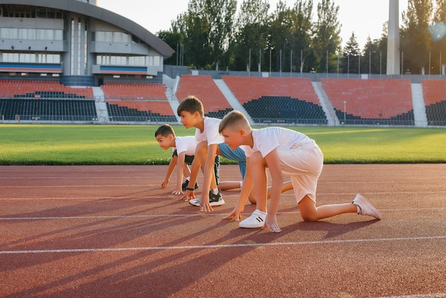 A large group of boys ' children are taught by a coach at the start before running at the stadium during sunset A healthy lifestyle