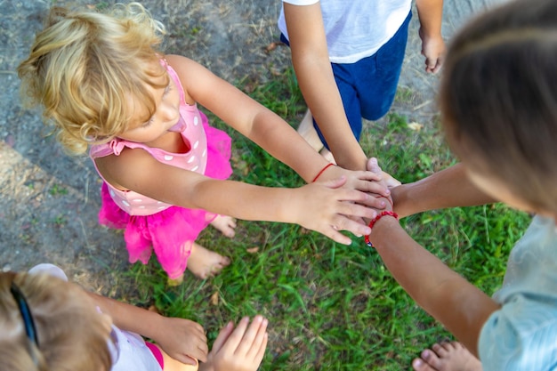 Photo a large group of children boys and girls stand together in a circle and put their hands together setting themselves up and raising team spirit before the game