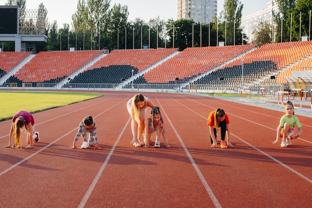 A large group of girls are taught by a coach at the start before running at the stadium during sunset A healthy lifestyle