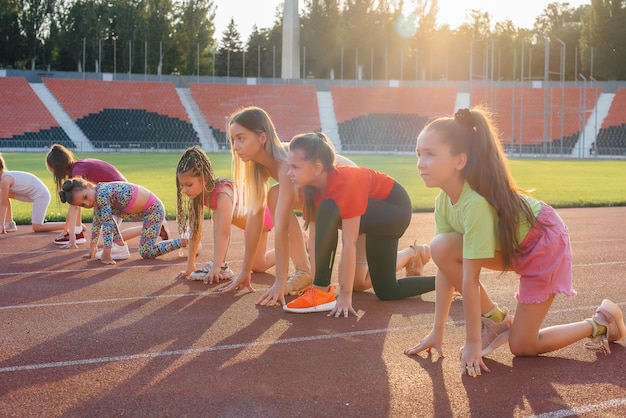 A large group of girls are taught by a coach at the start before running at the stadium during sunset A healthy lifestyle