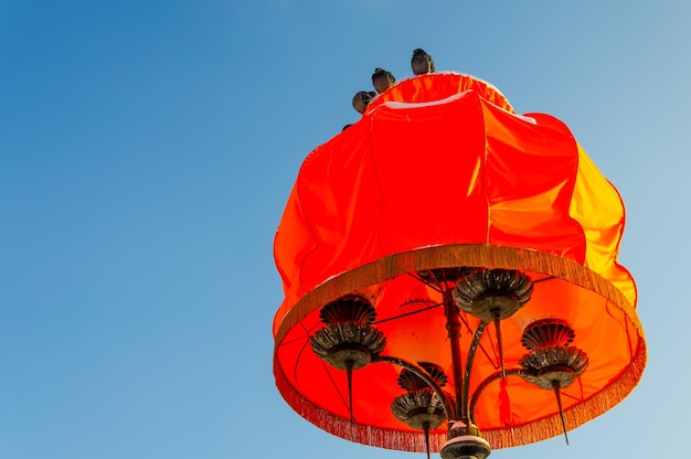 A large lampshade on a street lighting pole.