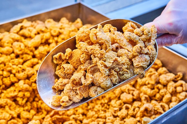 Large metal bin of fresh chicharrones with full pail