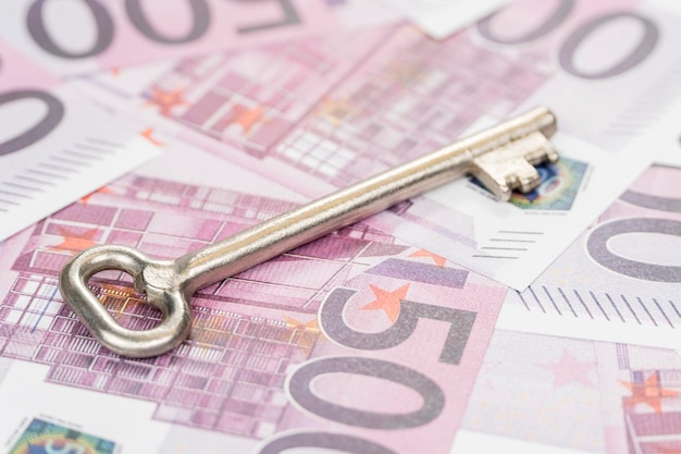 Large metal key on the background of money in denominations of five hundred euro