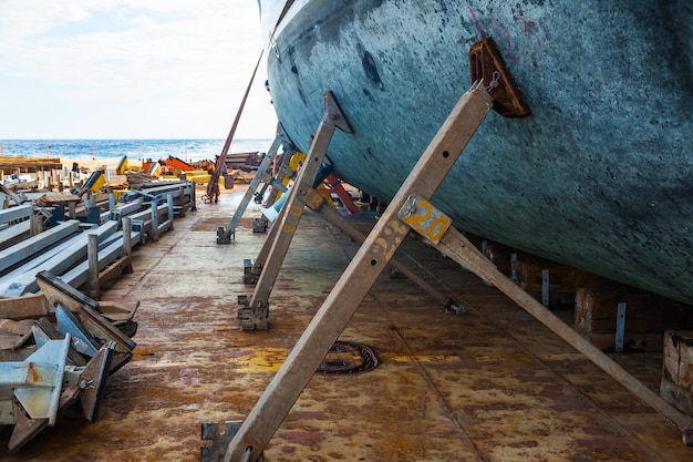 A large motor yacht is in dry dock and is supported by metal supports