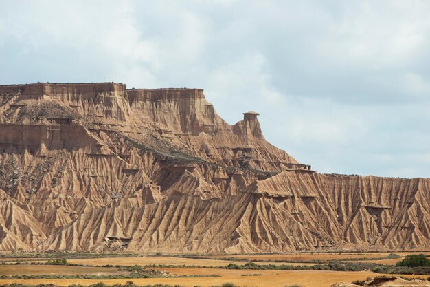 A large mountain range with a rocky barren landscape The sky is cloudy and the sun is shining