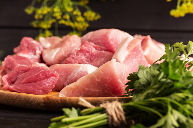 Large piece of beef meat on the board. Black background, parsley. Photo for a cooking recipe