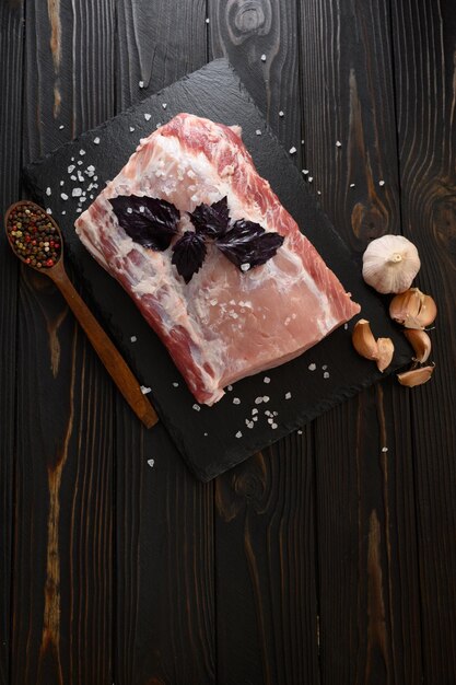 A large piece of pork loin with basil on a rustic dark background