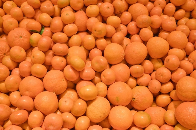 Large pile of ripe oranges and tangerines on market counter Food background Fruit harvest concept