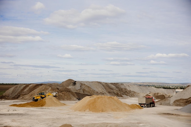 A large pile of sand is in the foreground and the word sand is on the front of the truck.