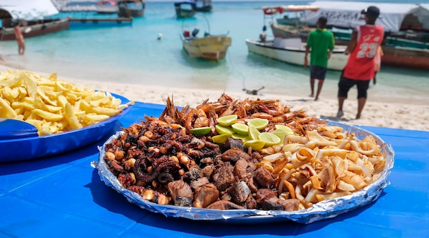 Large plate with a mix of grilled seafood shrimp, octopus, tuna fish, squid. BBQ exotic food on the beach. Selective focus.