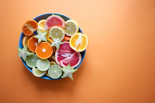 Photo large plate with sliced citrus fruits on orange background