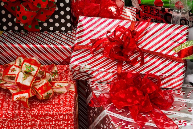 Large presents wrapped in colorful papers with bows in a pile ready for Christmas.