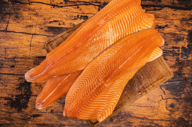 Large raw salmon fillets on a wooden board