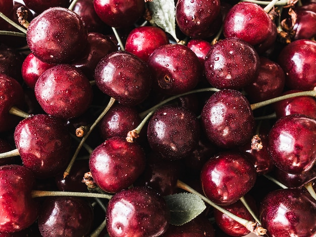 Large ripe cherry berries with leaves and drops of water background. Natural summer food background