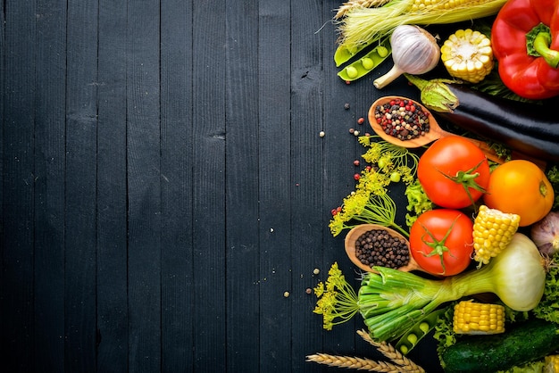 A large selection of raw fresh vegetables and spices On a black wooden background Top view Free space for your text