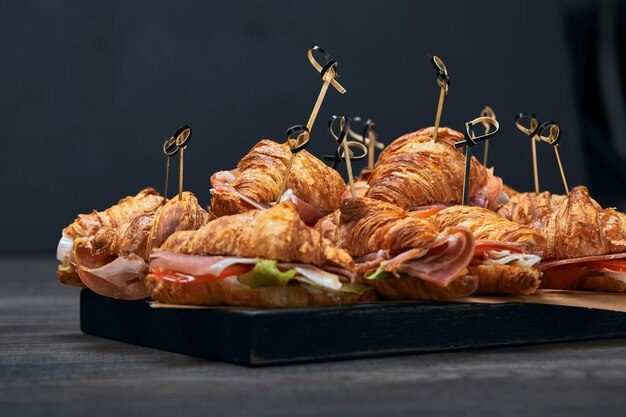 A large set of many croissants with different fillings laid out on a table on a gray background seth