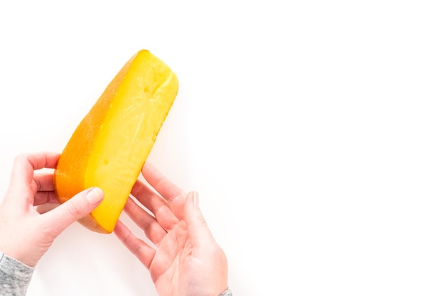 Large slice of smoked gouda cheese on a white background.