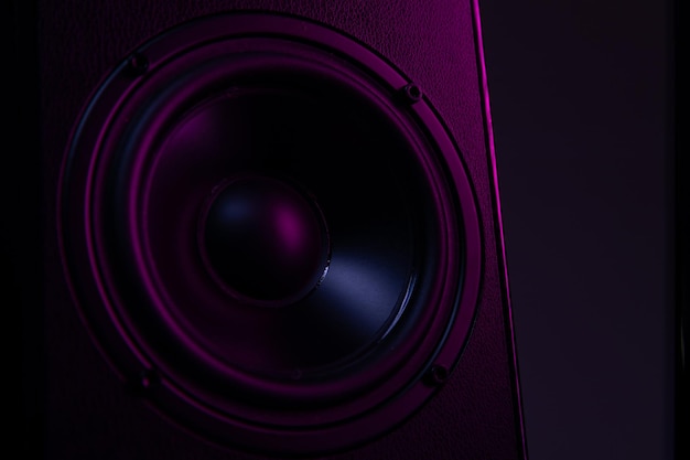 Large speaker closeup on a black background with violetpurple illumination closeup music playback on