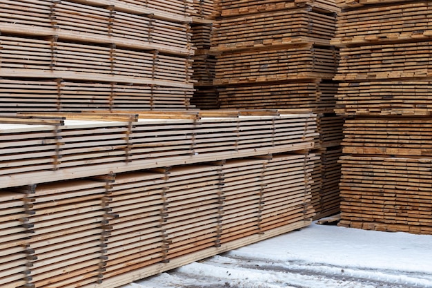 Large stacks of wooden planks background with selective focus and linear perspective winter oudoor