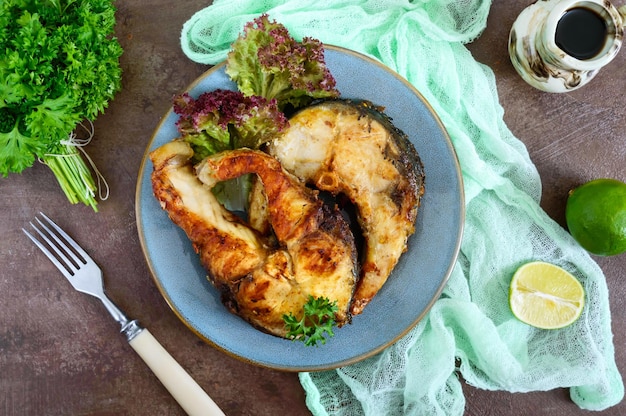 Large steaks of grilled fish with lettuce on a plate The top view