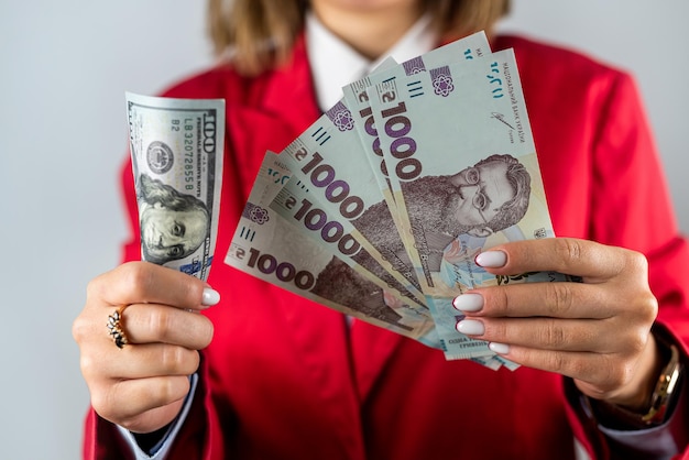 Large sum of dollars closeup and hryvnias in the hands of a beautiful young woman